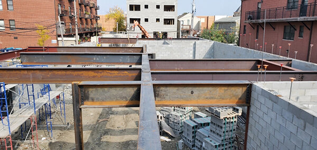 Structural steel beams framing a masonry building on an urban site